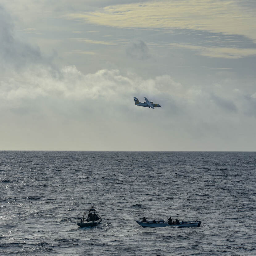 Go-fast en boot met smokkelaars en drugs op volle zee. Vliegtuig vliegt eroverheen.