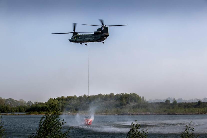 Archieffoto van een Chinook die een bambi bucket vult.