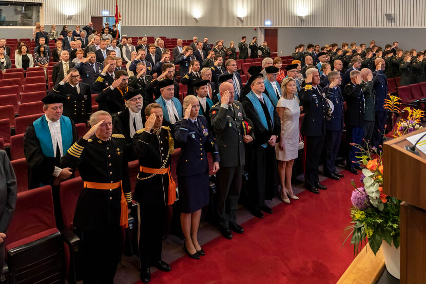 De minister naast officieren in opleiding, in een collegezaal.