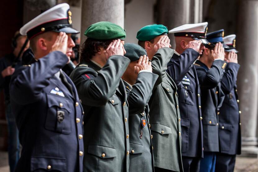 Militairen van verschillende krijgsmachtdelen salueren.