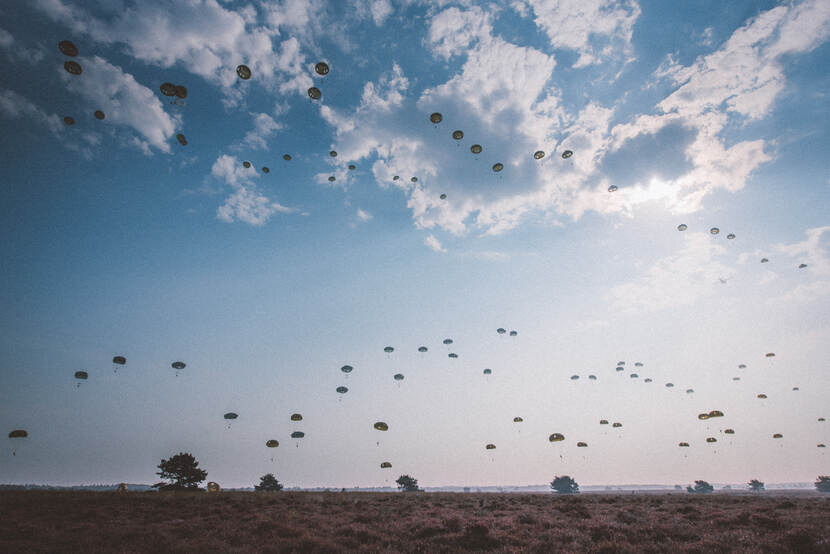 Militaire parachutisten landen na hun dropping op de heide.