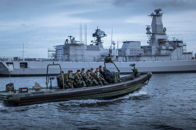 Rubberboot met mariniers vaart voor marineschip.