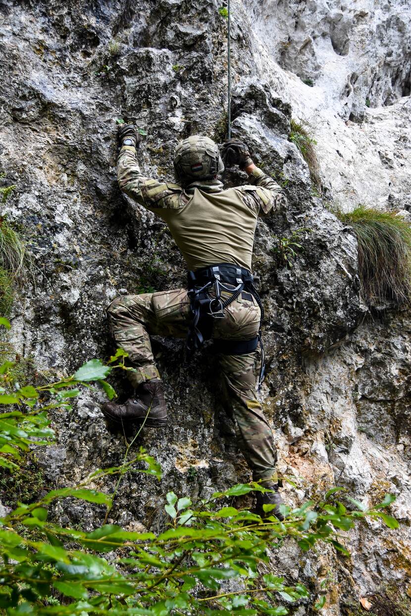 Militair klimt tegen steile berg aan.