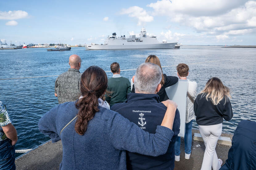 Mensen op de wal kijken naar wegvarende Zr.Ms. Tromp.