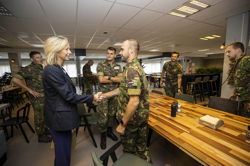 Minister Kajsa Ollongren geeft militair een hand, anderen kijken toe.