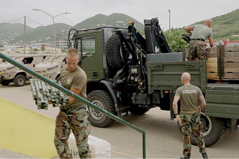 Mariniers bereiden zich voor op het leveren van noodhulp. Links op de achtergrond Anaconda-voertuigen.