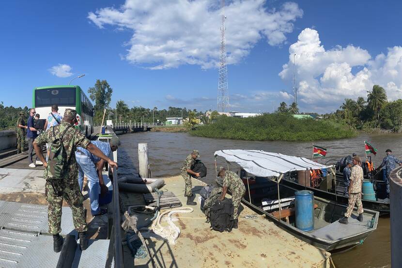 Militairen en burgers aan het werk op de oever van een rivier.