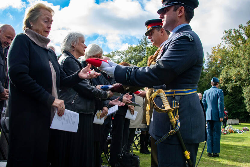Britse militair geeft opgevouwen vlag aan vrouw.