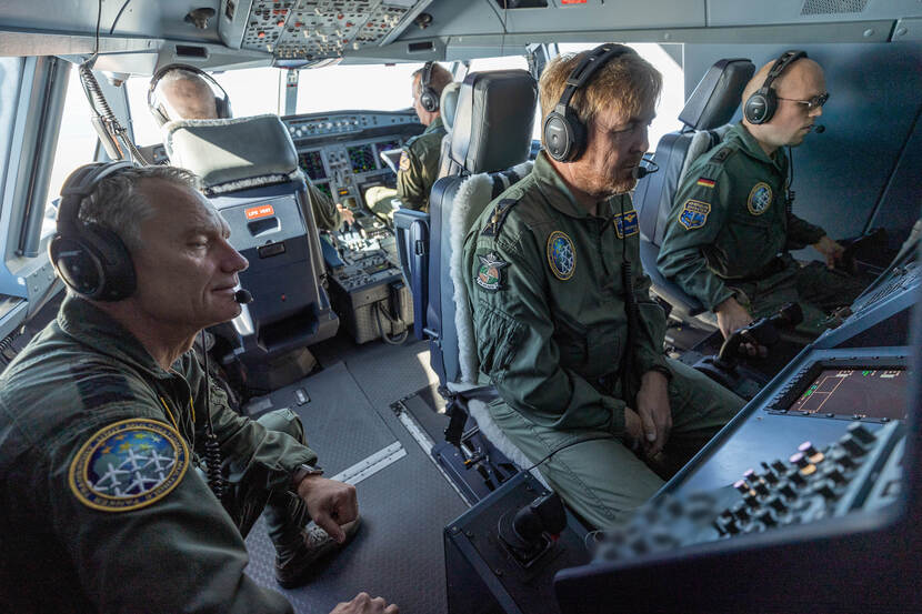 Koning Willem-Alexander kijkt op een beeldscherm in een MRTT-tankvliegtuig, militairen zitten naast en achter hem.