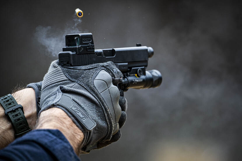 Beeld van handen die een pistool afvuren tijdens een BSB-oefening.