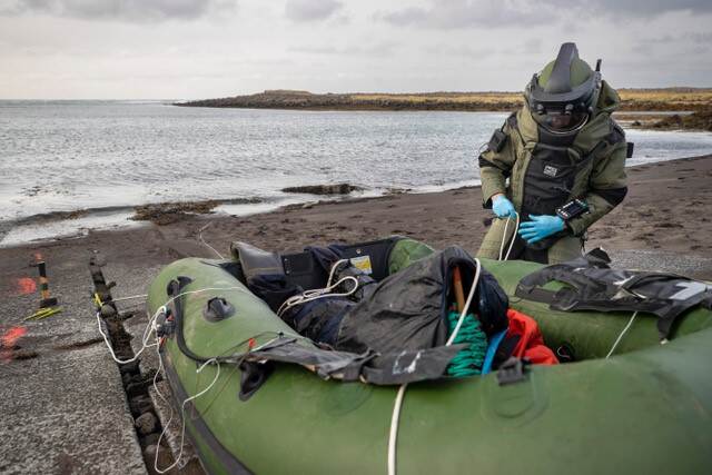 Een EOD'er in een bompak onderzoekt een geïmproviseerd explosief in een motorbootje.