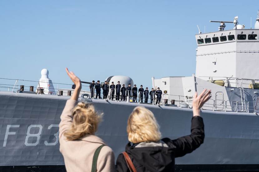 Vrouwen zwaaien naar schip. Bemanning op het dek.