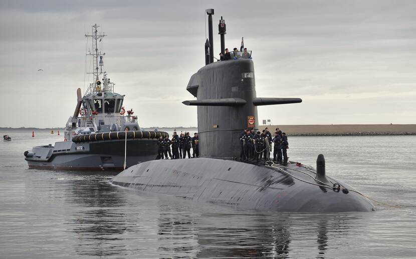 Onderzeeboot, bemanningsleden staan er bovenop. Marineboot ligt erachter.