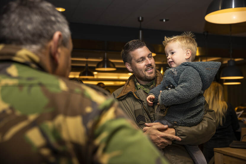 Thuisgekomen militair met klein kind op de arm.