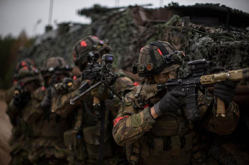 Archieffoto van gecamoufleerde militairen met wapen in de aanslag.