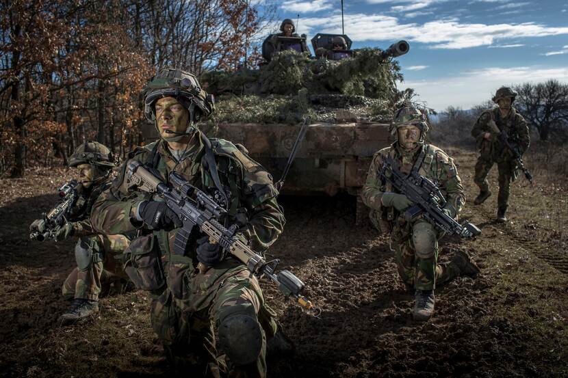 Archieffoto uit 2016: militairen, gecamoufleerd en bewapend, poseren bij een tank.