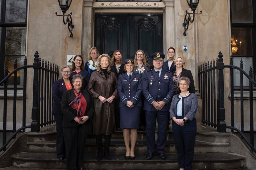 Groep vrouwelijke buitenlandse officieren rondom minister Ollongren op trap ministerie.