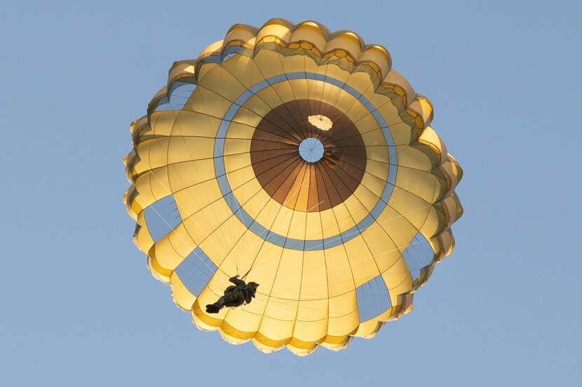 Een militair van de Defensie Paraschool hangt aan een nieuwe parachute.