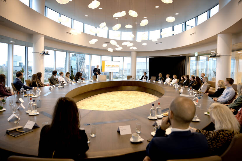 Deelnemers aan het Young Boards Community-event zitten aan een ovalen vergadertafel in de boardroom van advocatenkantoor Stibbe in Amsterdam.