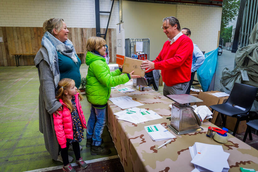 Vrouw en kinderen brengen postpakket naar militaire postorganisatie.