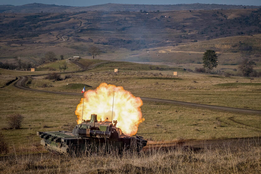 Tank geeft vuur in heuvelachtig terrein.