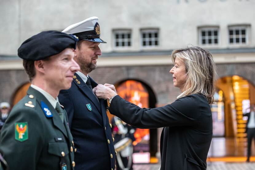 Minister speldt onderscheiding op bij militair. Naast hem een andere gedecoreerde.