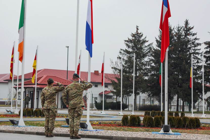 2 Nederlandse militairen salueren voor een rij vlaggen.