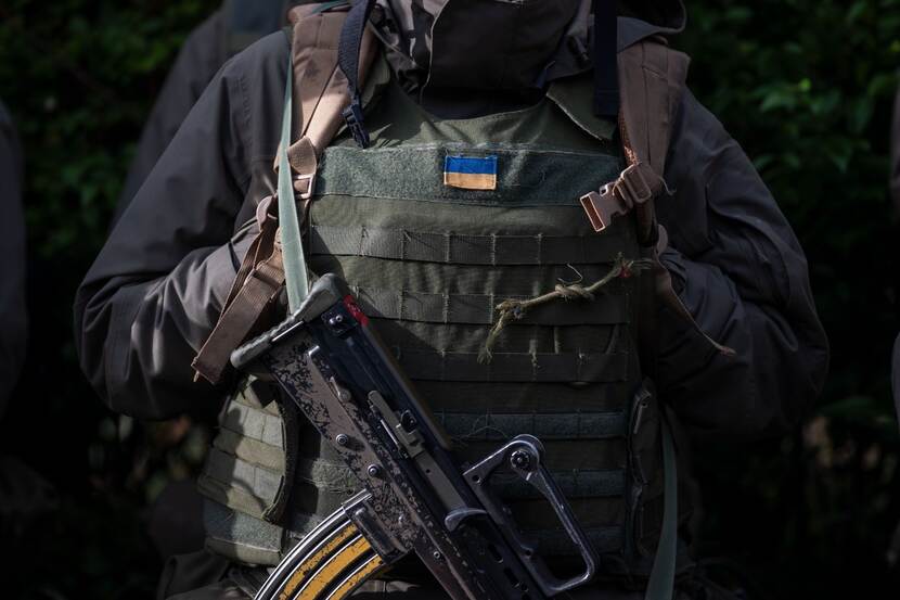 Militair uit Oekraine gezien vanaf de hals.  Op het uniform staat Oekraiens vlaggetje.