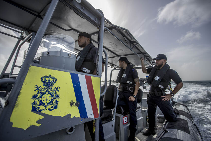 3 militairen op een rubberboot op open zee.