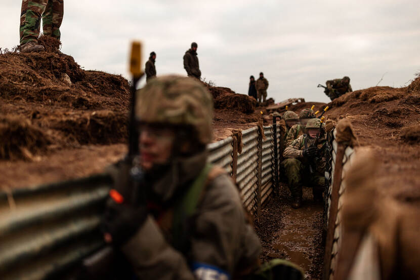 Militairen zitten geknield in trenches tijdens een training in Groot-Brittanniē.