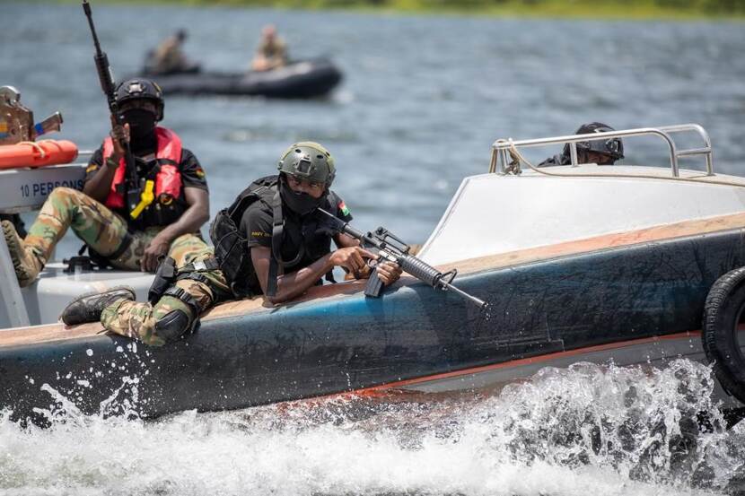 Bewapende militair klimt uit klein bootje.