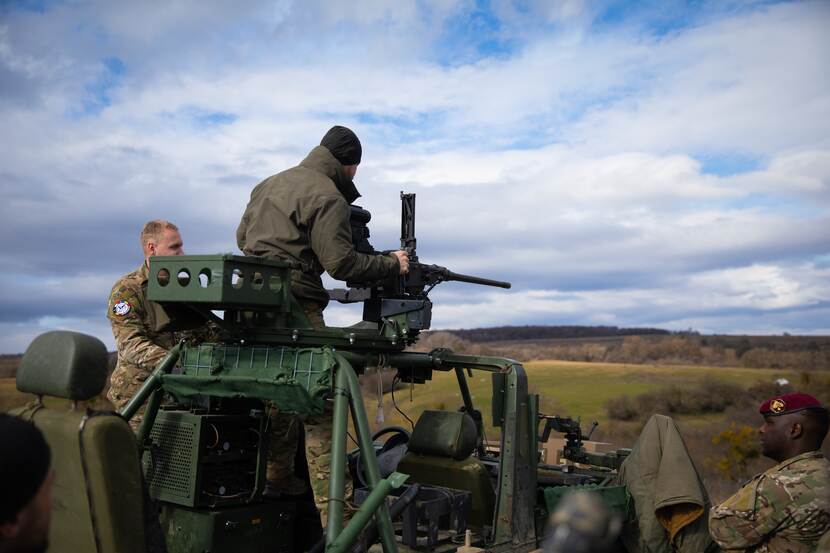 Militairen bezig met wapen op voertuig.