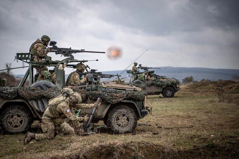 Militairen vuren vanaf voertuigen.