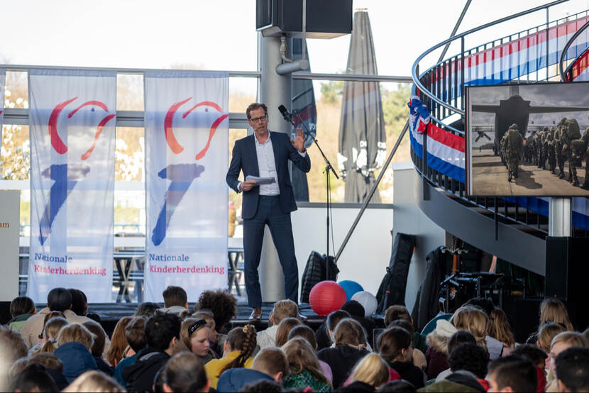 De staatssecretaris staat op een verhoging voor een klas scholieren.