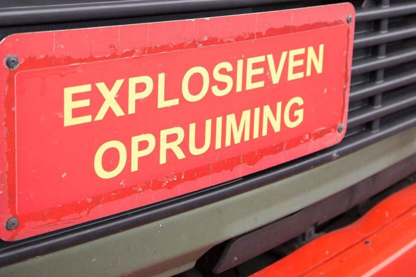 Rood bord met gele letters met de tekst 'Explosieven opruiming'.