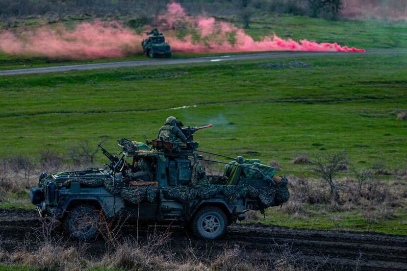 Legervoertuig met militair die een wapen afvuurt op een open vlakte in Litouwen.