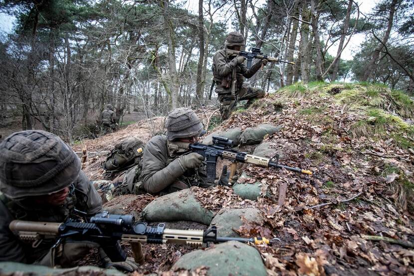 Gecamoufleerde mariniers kijken door het viziervan hun wapen.