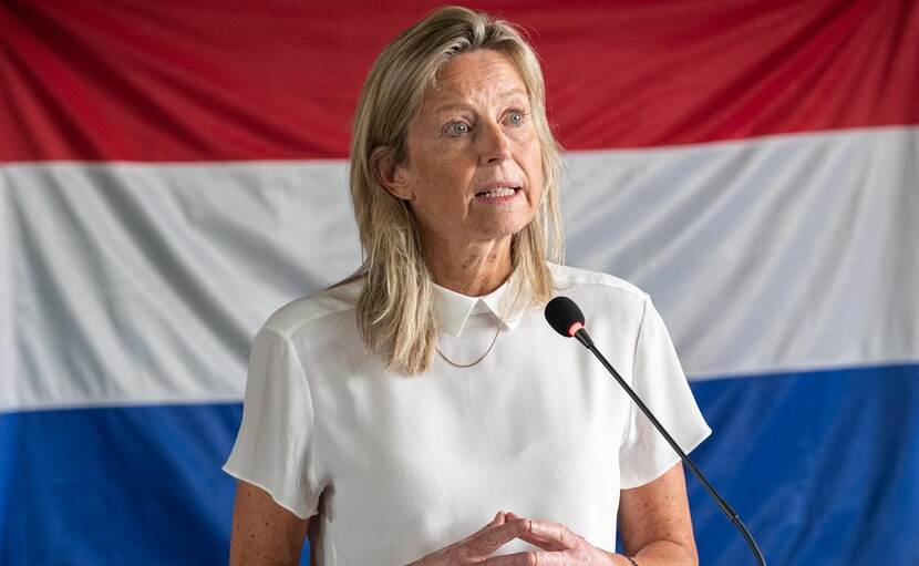 Minister Kajsa Ollongen staat voor een Nederlandse vlag.
