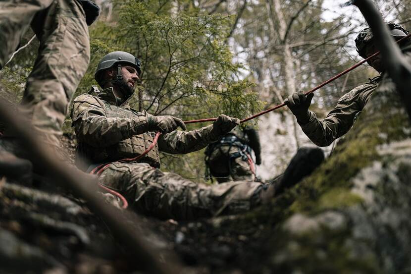 Militairen in een bos houden veiligheidslijn vast.