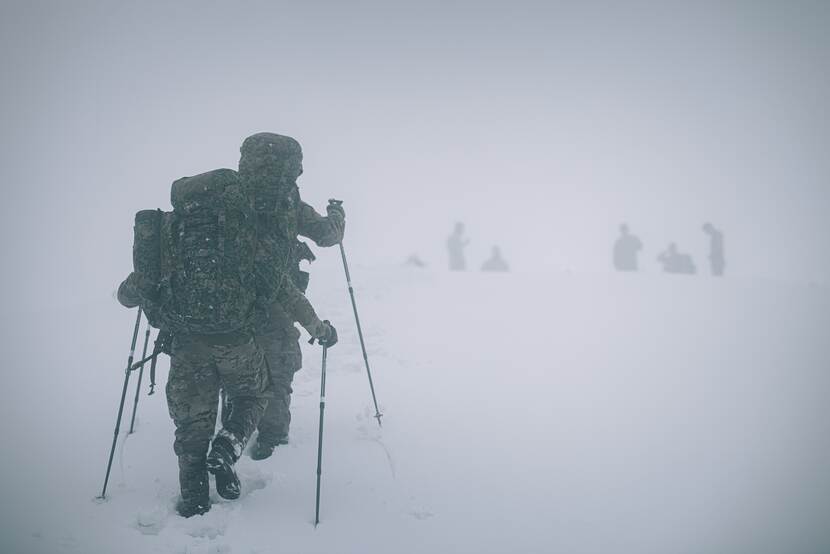 Militairen lopen in de sneeuw.