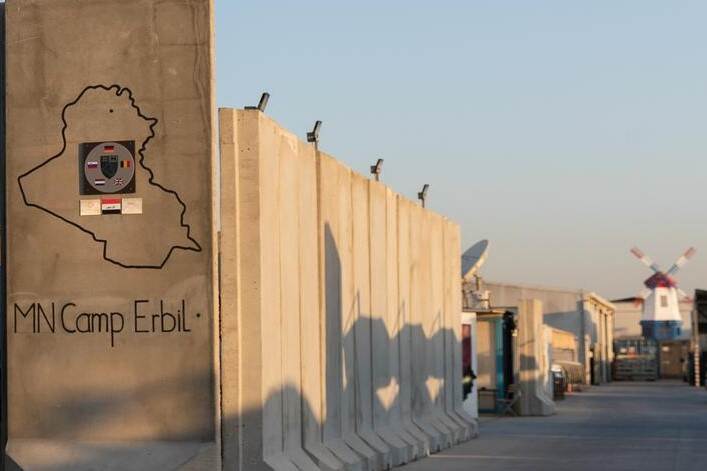 Betonnen kolos met opschrift MN Camp Erbil. In de verte een molen in kleuren NL-vlag