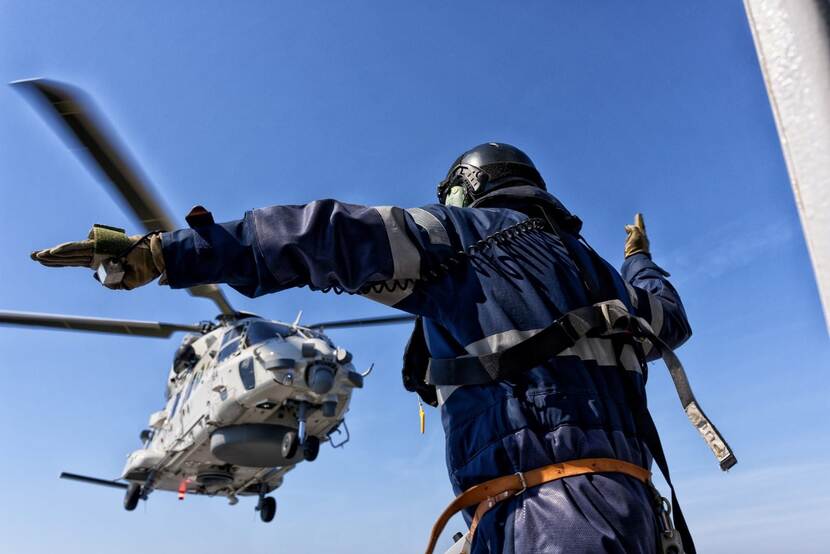 Landingsassistent met boven hem een landende helikopter.