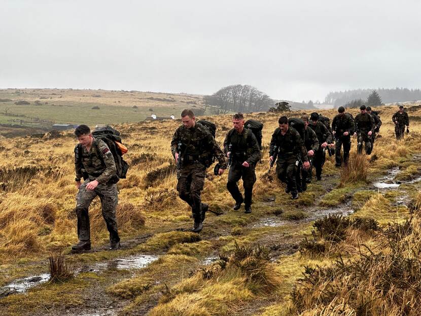 Mariniers lopen door drassig landschap.