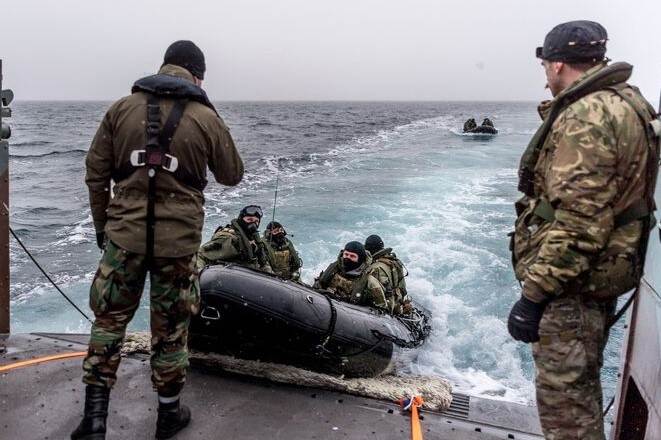 Rubberboot met mariniers wordt binnengetrokken op dek.