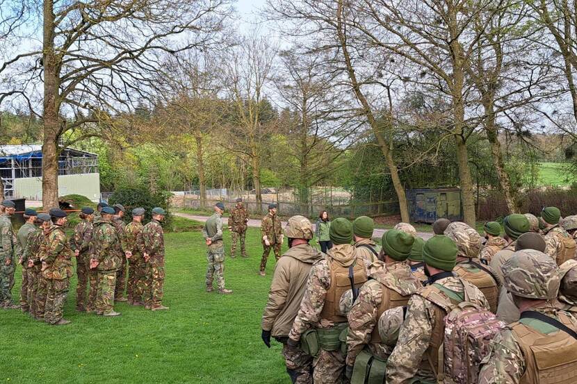 2 groepen met militairen tussen bomen op grasveld.