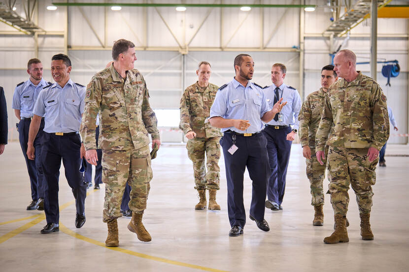 Amerikaanse en Nederlandse militairen lopen in een lege zaal.