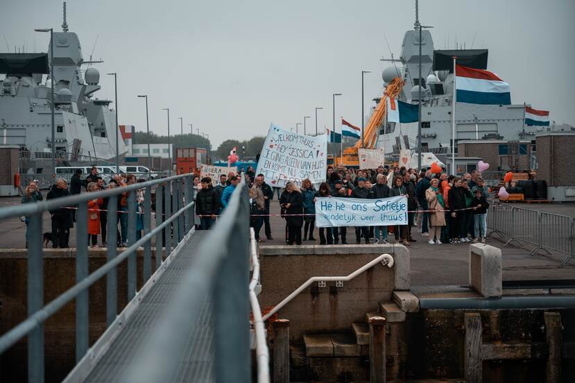 Mensen met spandoeken bij aankomst schip.