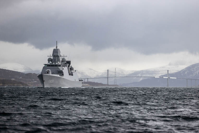 Marineschip vaart tussen besneeuwde bergen.