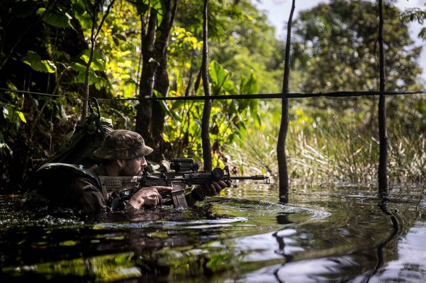 Militair waadt door water in een jungle.