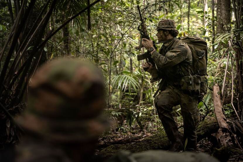 Militair met wapen in een jungle.